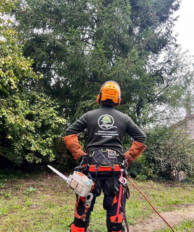 Steven, élagueur paysagiste, en tenue de grimpe avec sa tronçonneuse